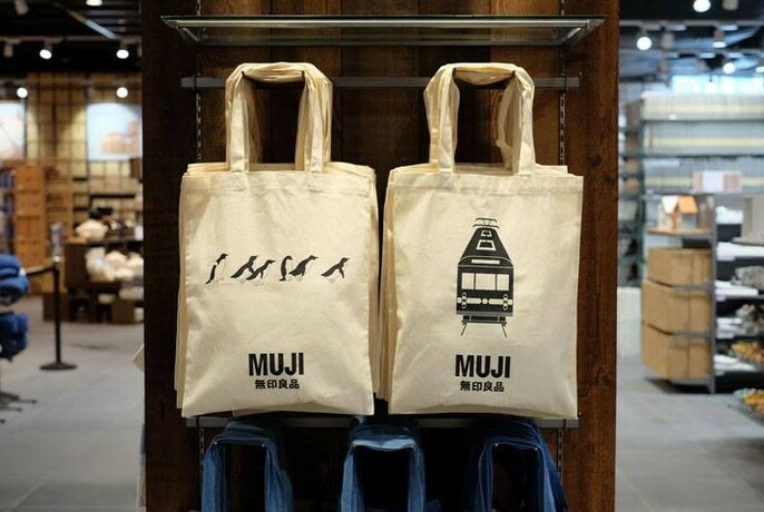 Two Muji tote bags hanging in the store.