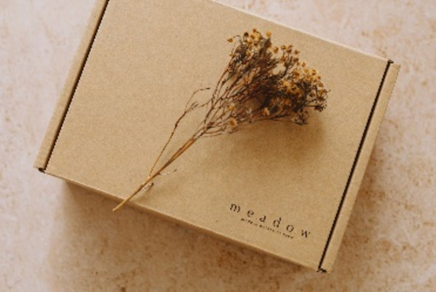 A brown box with a sprig of camomile resting on the top. 