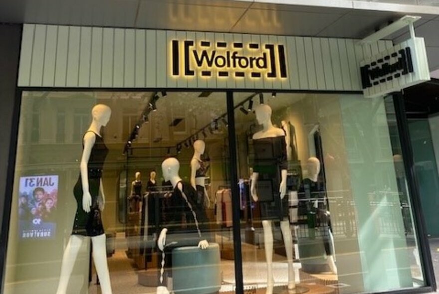 Wolford boutique window viewed from the street, with signage and mannequins dressed in black.