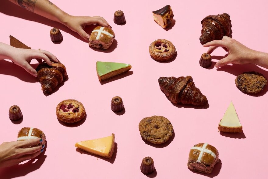Baked pastries and cakes displayed on a pink background with four hands at the edges of the image reaching in to pick up the items.