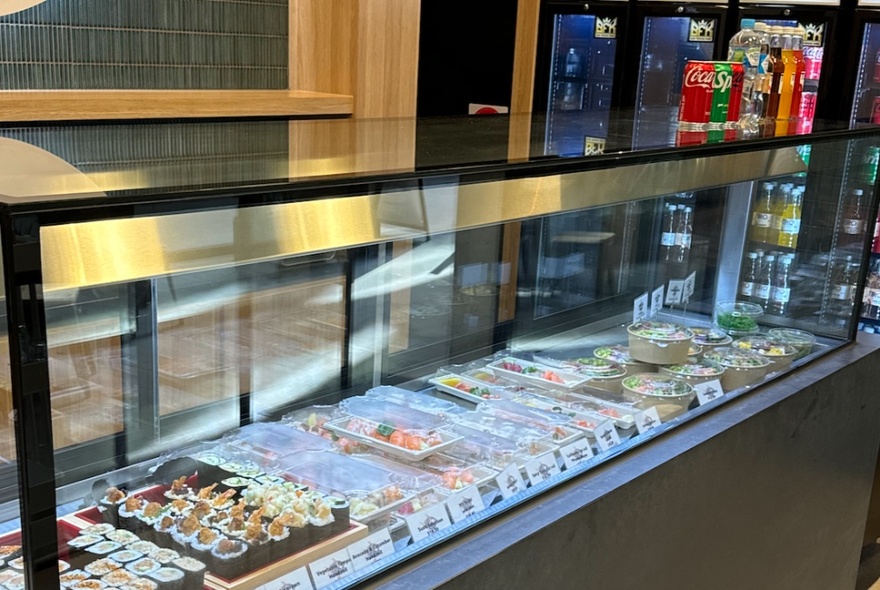 The glass display counter at Moonfishh filled with trays of sushi and nori rolls.
