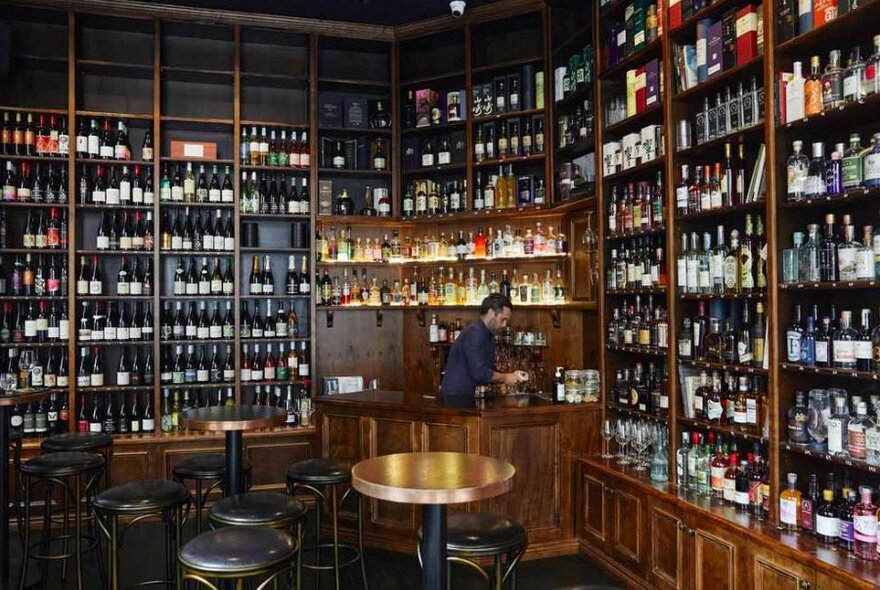 A man behind the counter at a bottle shop bar.