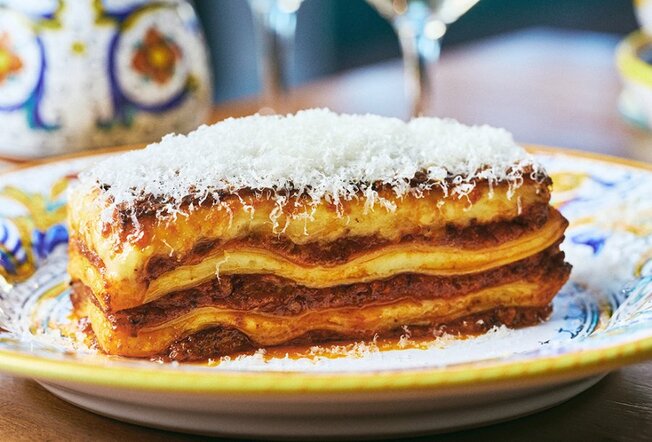 A slice of lasagne topped with grated parmesan cheese.