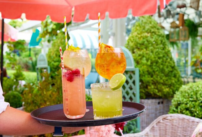A tray full of colourful cocktails in a beer garden.