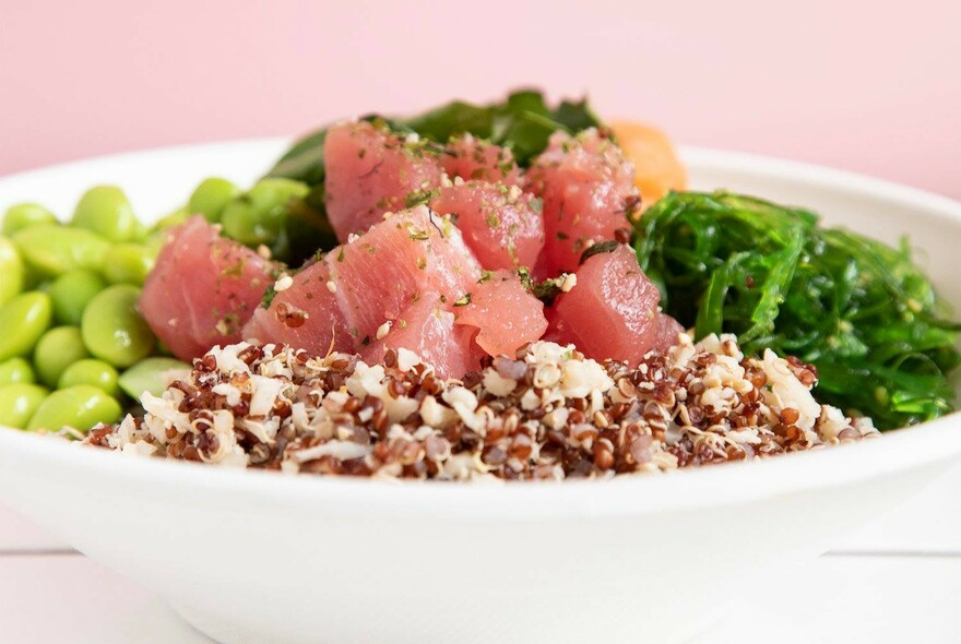 White poke bowl with soybeans, salmon, quinoa and vegetables.
