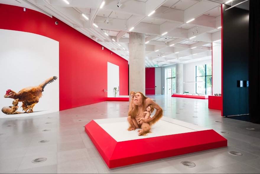Orangutan-person sculpture on a red plinth in a white gallery space