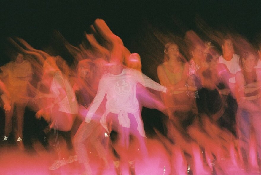 A blurred shot of people dancing against a black background.