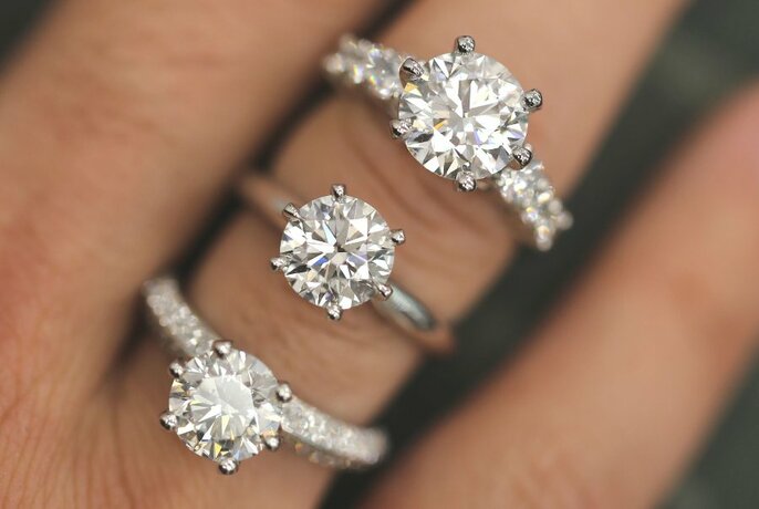 Three examples of diamond engagement rings on one finger. 