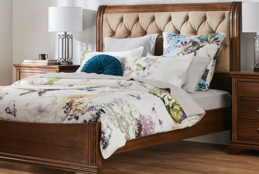 Wood-framed double bed with quilted headboard, floral linen and cushions.