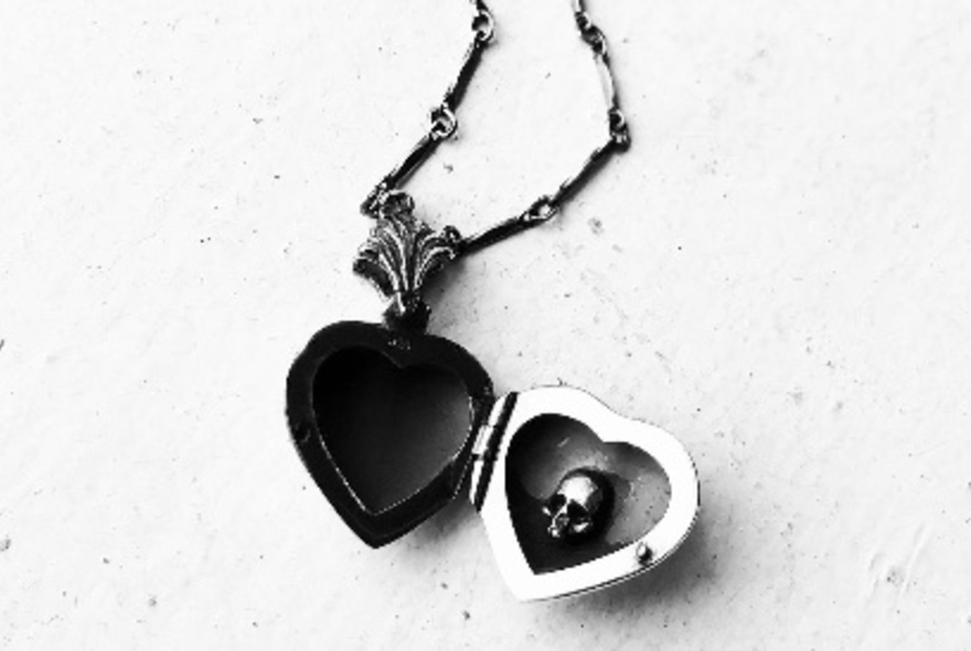 A gothic-style black heart locket with a skull inside. 
