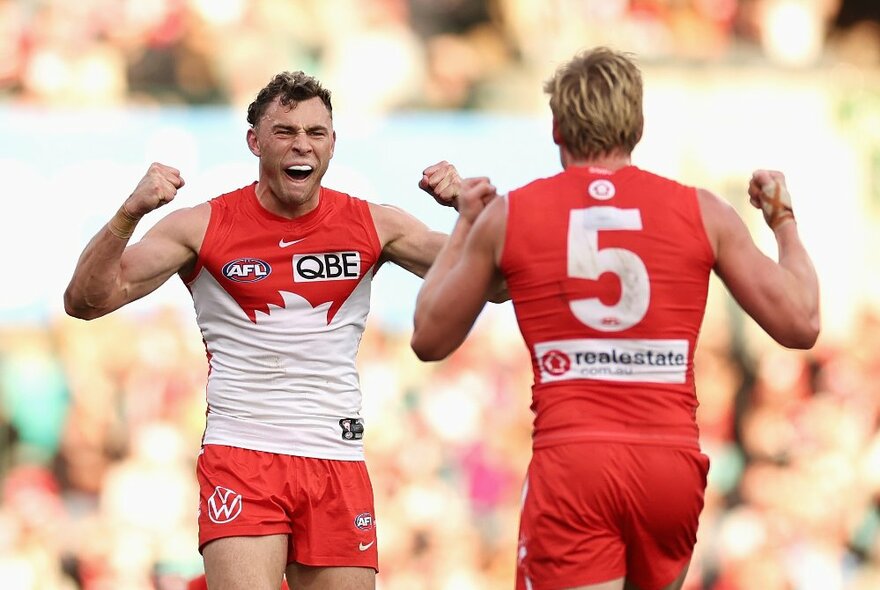 Two Sydney Swans AFL football players raising their fists and yelling during a match.