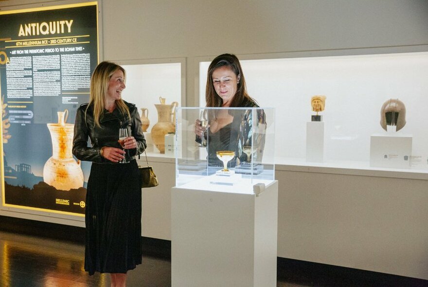 Interior of the Hellenic Museum with two women looking at a display cabinet.