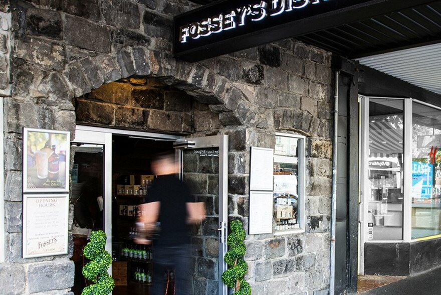 A bluestone bar exterior with a blurred person entering the door. 