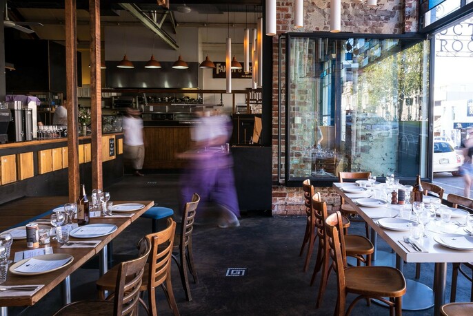 Windows opening onto Errol Street North Melbourne and tables set for meals at Auction Rooms coffee roastery and cafe.
