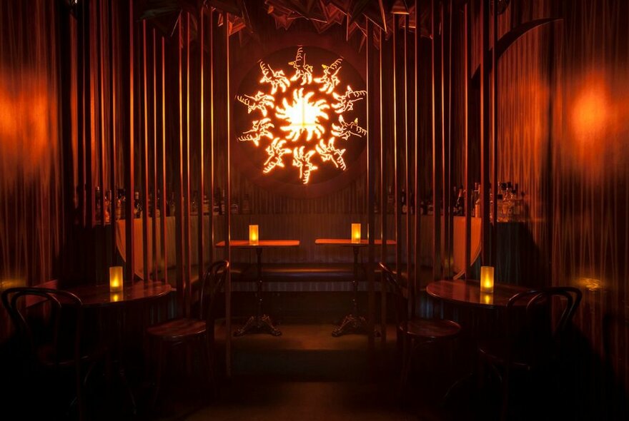 Deluxe bar interior with candles on tables and central decorative light.