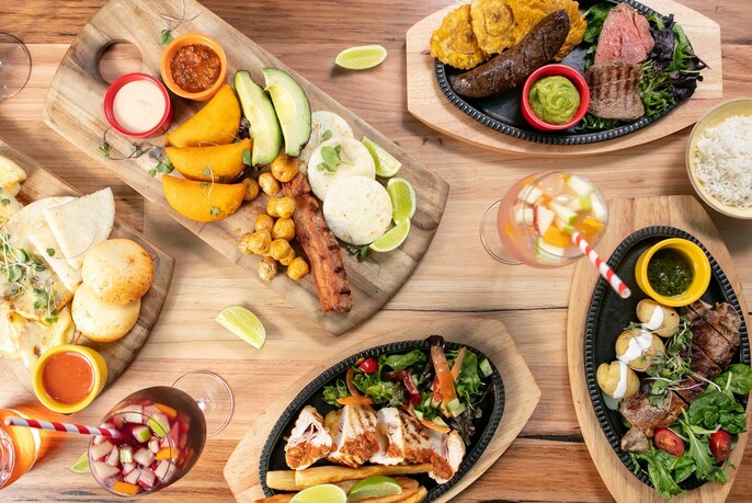 Overhead view of plates of Colombian food, with drinks, on a table.