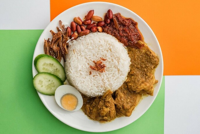 A white plate of nasi goreng on a green and orange background.