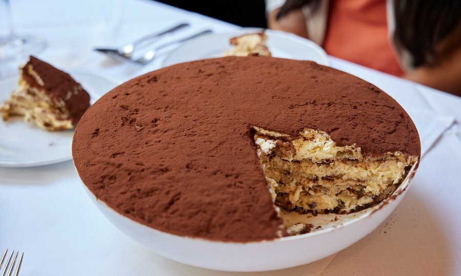 A giant bowl of tiramisu with a slice cut out.
