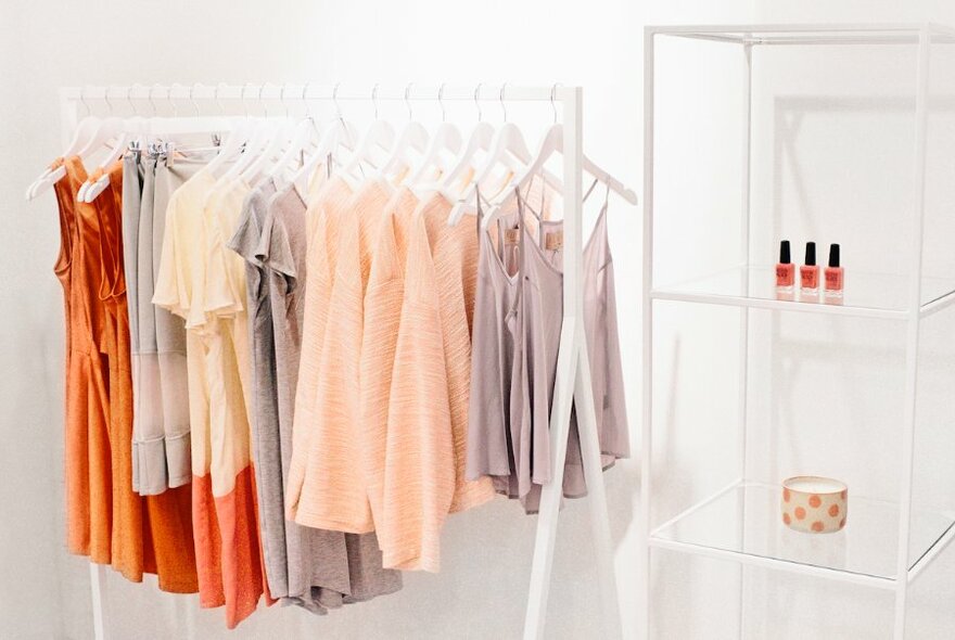 A clothing rack and a display cabinet in a minimalist, white store.