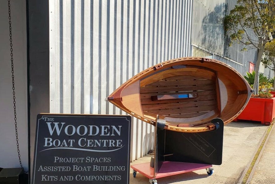 Exterior of the Wooden Boat Centre with small wooden boat on display and signage.