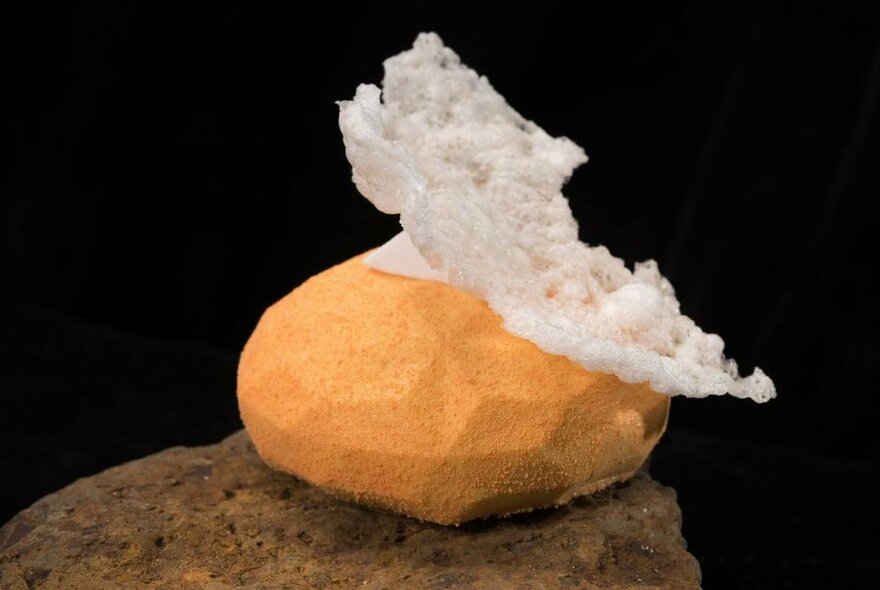 A yellow bevelled edge cake perched on a stone with a white airy top.