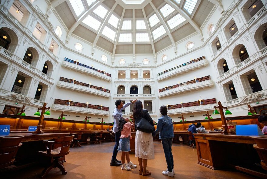 People looking up at the domed ceiling of the State Library Reading Room.