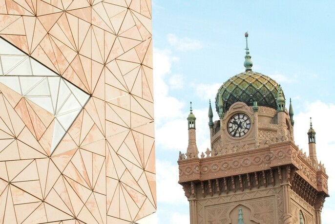 Ornate architecture of dome and tower of Forum Melbourne, with Federation Square in the foreground.