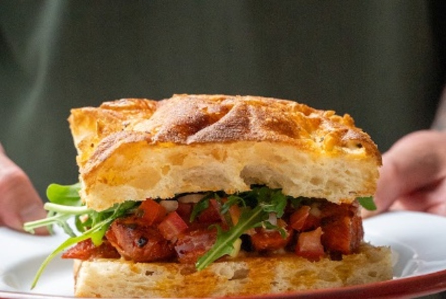 Close-up of a toasted vegetarian focaccia sandwich on a white plate. 
