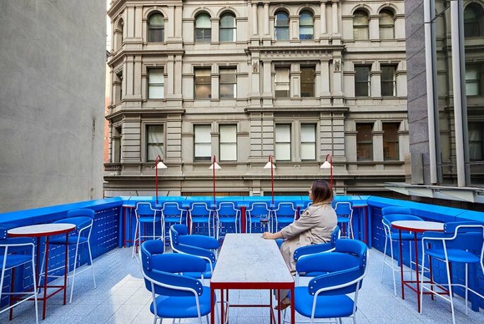 Rooftop bar in a laneway with bright blue seating.