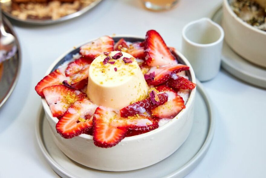 A bowl of strawberries topped with a panna cotta