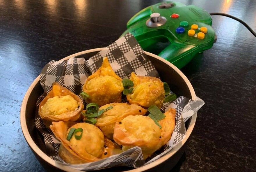Bowl of fried snack foods with a PlayStation game controller in the background.