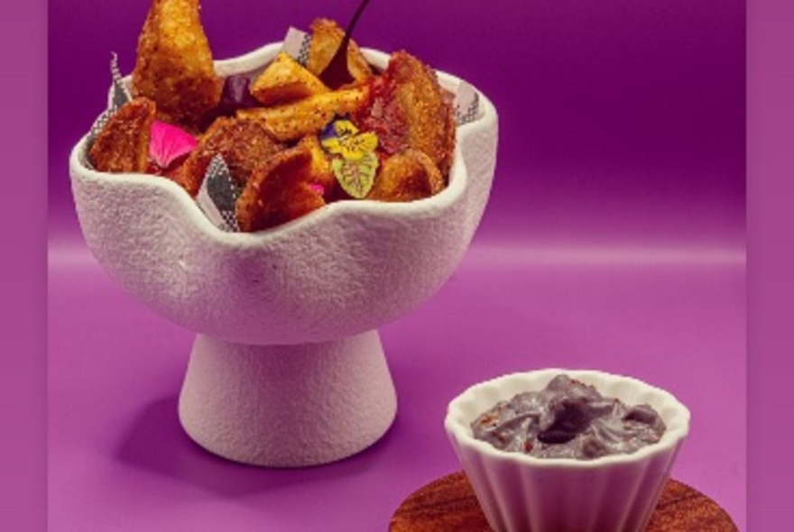 A cactus-shaped bowl filled with fried snacks next to a bowl of purple dip.