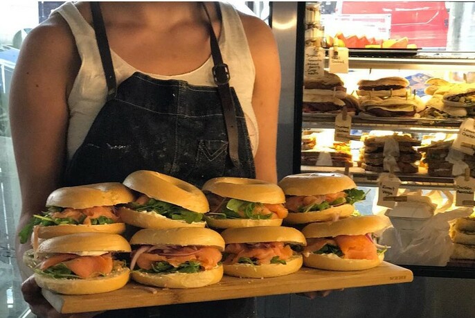Person carrying a tray of smoked salmon bagels.