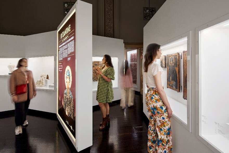 People walking around in a museum space and looking at exhibits on display.