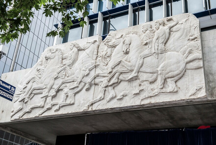 Exterior of the Greek Centre, featuring a carved stone artwork of men riding horses.