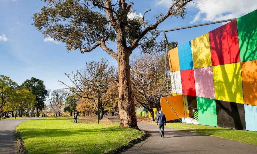
The colourful cube exterior of the Melbourne Museum building surrounded by gardens.