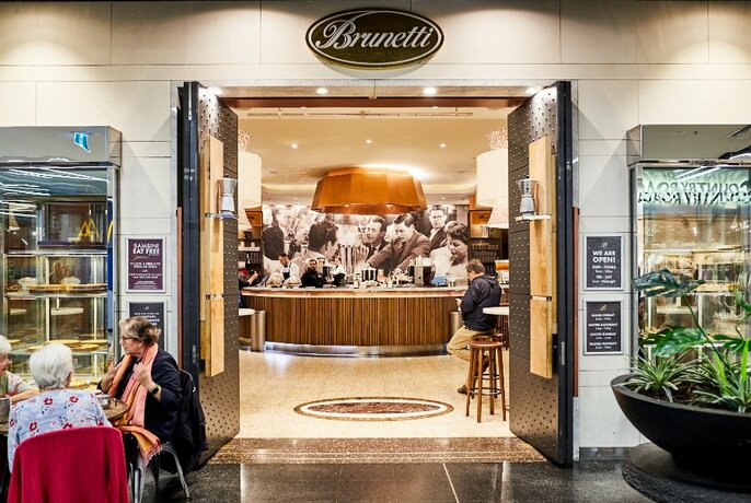 Entrance to Brunetti's showing tables outside, large doors and the coffee bar counter.