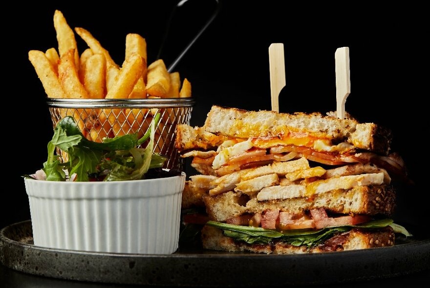 A large toasted club sandwich served with salad and chips.
