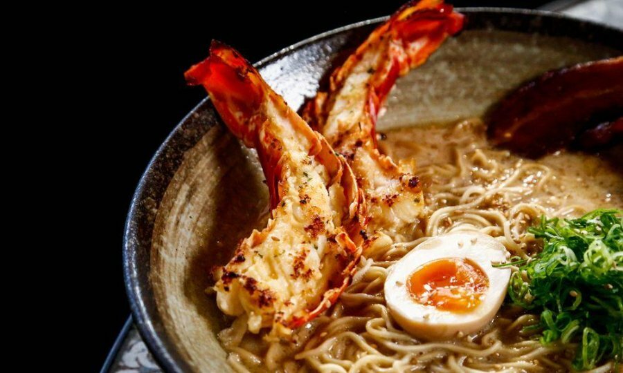 A bowl of ramen with lobster tails on top