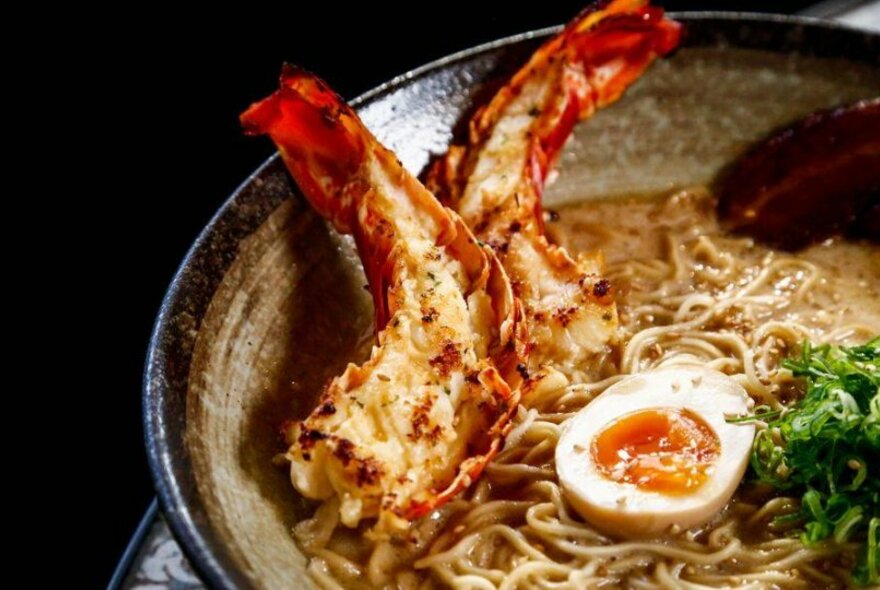 A bowl of ramen with lobster tails on top