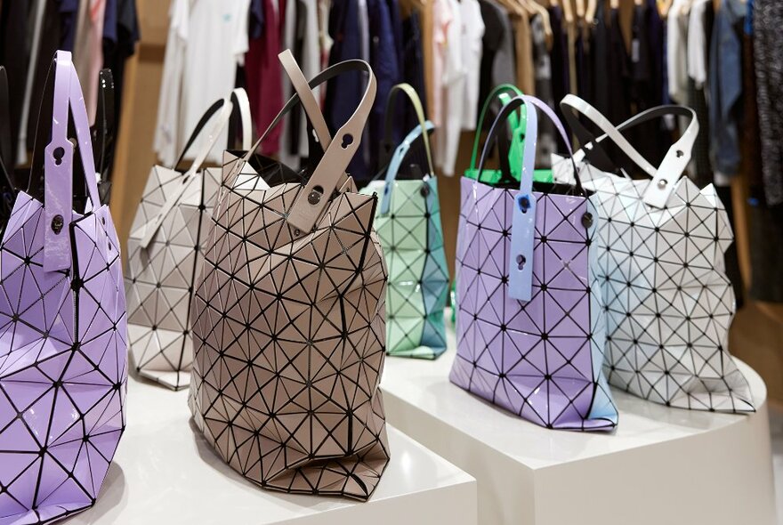 A shop display of different coloured bags with plastic geometric panels.