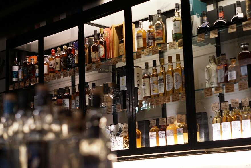 A view of a dimly-lit bar with shelves of whiskies.