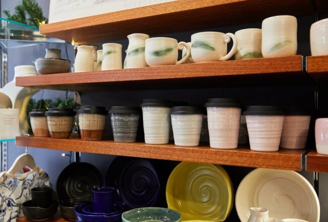 Wooden shelves holding ceramic mugs, keep cups and bowls