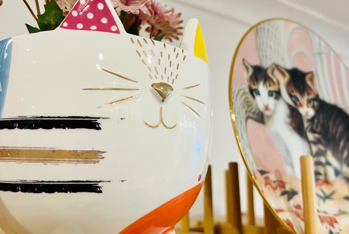 Cat plate and vase displayed on a shelf.