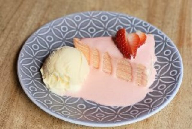 Slice of cake as a dessert with cream, ice cream and a strawberry garnish.
