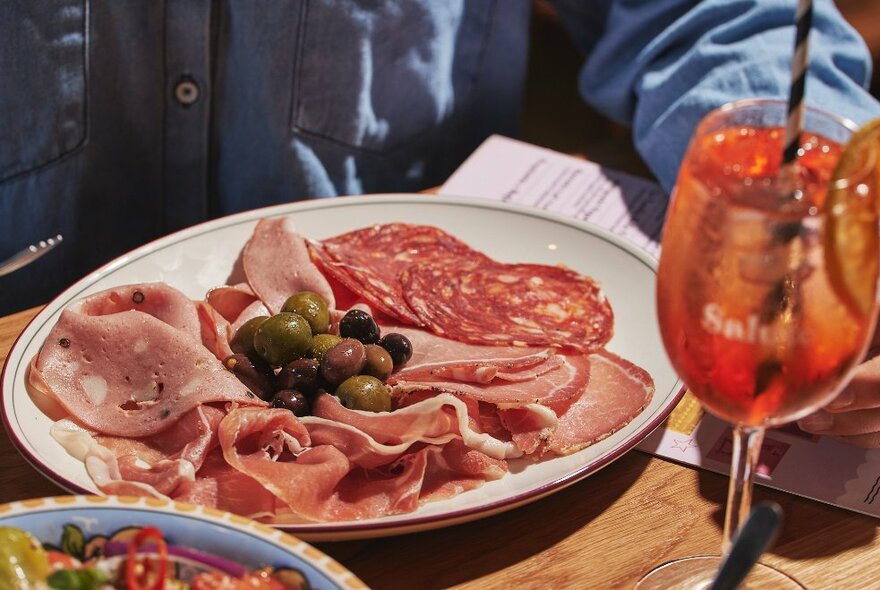 A plate of salumi and olives and an Aperol spritz.