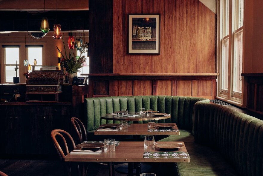 Comfortable banquette seating around tables in a wood panelled interior of a restaurant.