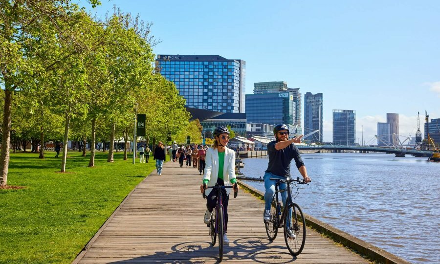 Two people riding bikes along the Yarra River. 