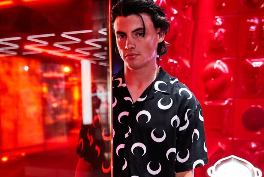 A model surrounded by red plastic wearing a black shirt with white moons