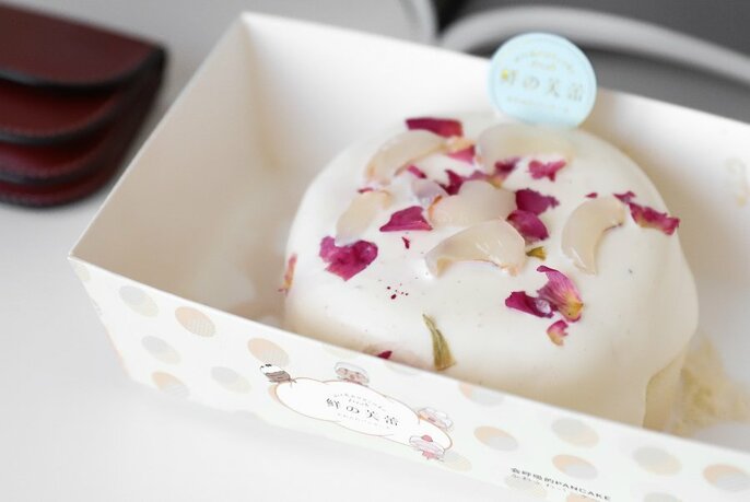A white coated soufflé dessert in a box with white and pink shavings on top